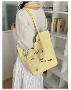 Détail d'un cabas jaune avec broderie de chien et poignée tissée colorée