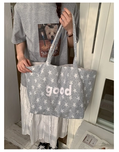 Detail of grey canvas tote bag featuring white star pattern and good lettering