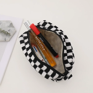 Macro detail of checkered knit cosmetic bag featuring metal zipper and soft lining