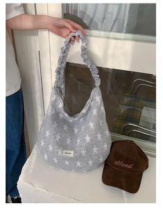 Detail of grey star pattern tote bag with ruffled strap and lace brand label accent