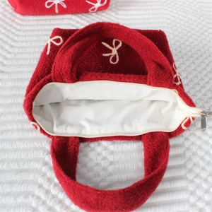 Détail du sac à main en feutre rouge avec broderie nœud blanc et fermeture zippée