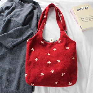 Detail of red knit tote bag with white bow embroidery and classic plaid lining