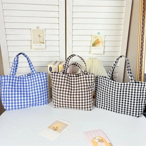Detailed view of checkered canvas tote bags in blue, brown, and black patterns