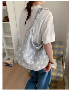 Detail of light grey shoulder bag with white star patterns and ruched strap design