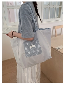 Close-up of a large grey tote bag with a star patch and YOUR JOLLYHOUSE label on shoulder
