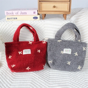 Détail des motifs de nœuds brodés sur des sacs en feutre avec fermeture à glissière