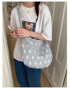 Gray canvas crossbody bag with white star pattern worn over the shoulder by a model