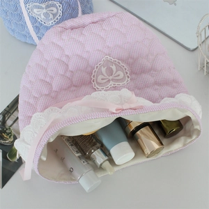 Detailed view of pink quilted lace organizer bag filled with cosmetic skin care products