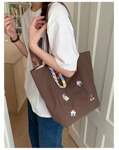 Gros plan d'un grand sac cabas marron avec broderie cartoon et cordon coloré
