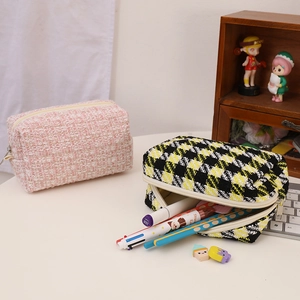 Detail of tweed makeup pouches showing pink and checkered patterns with metal zippers