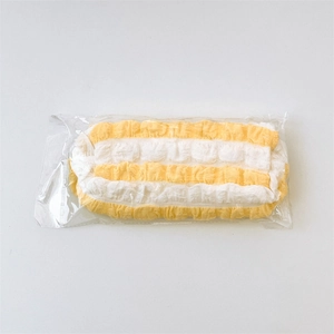 Detail of yellow and white striped puff pencil case in protective plastic packaging