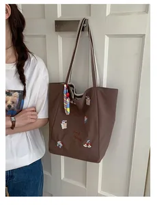 Détail du sac cabas en toile marron avec broderie d'ours et gri-gri arc-en-ciel