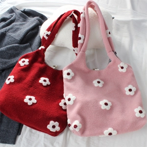Detail of knitted tote bag with floral patterns, checkered lining and snap closure