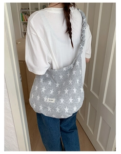 Detail of grey knitted crossbody bag with star pattern and ruffled shoulder strap