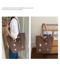 Détail macro du sac cabas en toile marron foncé avec broderie colorée et bandoulière robuste