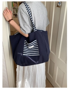Detail of canvas tote bag with striped straps and front pocket for school use