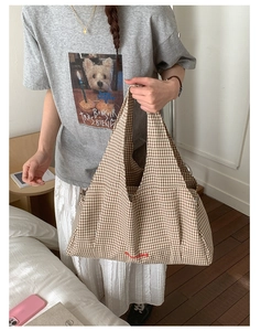 Detail of checkered tote bag with red letter embroidery and woven canvas texture