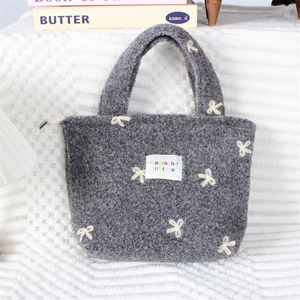 Détail du sac cabas en peluche grise avec broderie nœud blanc et fermeture zippée