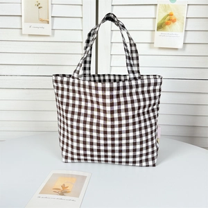 Detail shot of a black and white checkered canvas tote bag with dual top handles