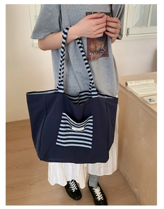 Detail of a large navy tote bag with blue and white striped pocket for daily commute