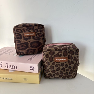 Detailed view of leopard print suede mini makeup bags with leather logo on a desk