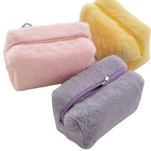 Plush macaron makeup bags in pink, yellow, and purple with fuzzy faux fur texture