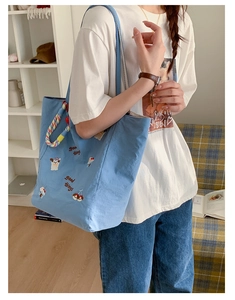 Détail de la broderie avec texte et chien de dessin animé sur un sac cabas en toile bleu