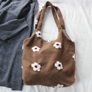 Close-up of brown textured tote bag featuring floral embroidery and snap button closure