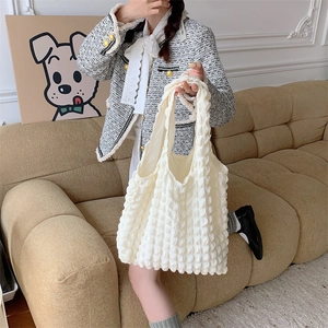Detailed view of cream-white bubble texture shoulder bag worn by model in cozy interior
