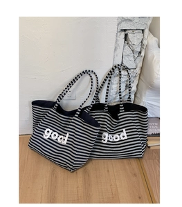 Close-up of high-capacity striped tote bags featuring white good lettering on knit fabric
