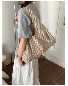 Detail of checkered canvas tote bag with Good Time red text on a shoulder strap model