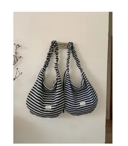 Detail of soft striped hobo bag featuring wide elastic ruched shoulder strap and woven label