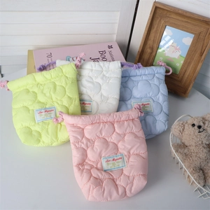 Detailed view of quilted heart pattern drawstring storage bags in various soft colors
