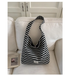 Close-up of the striped knit shoulder bag with white embroidered patch on a white sofa
