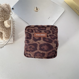 Detailed macro view of soft leopard print faux fur and the mayrabbit logo on a square pouch