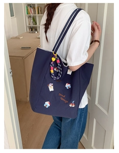 Détail du cabas en toile bleu foncé avec broderie cartoon et anses à rayures