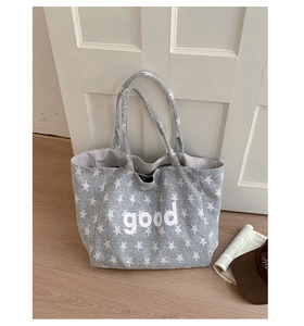 Detail of grey star print tote bag with GOOD text and casual striped shoulder strap