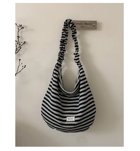Close-up of striped hobo bag featuring ruffled straps and Bonjour Merci fabric label