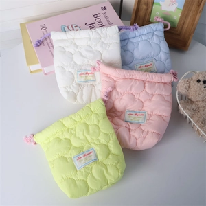 Detailed view of soft quilted drawstring pouches in four pastel colors on a desk