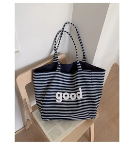 Close-up of a blue and grey striped canvas tote bag with good letter print on a chair