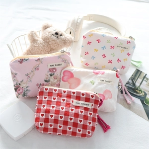 Mini floral and bow pattern fabric pouches with zippers and May Rabbit tags on white fabric