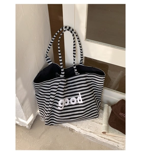 Detail of striped canvas tote bag showing white 'good' lettering and spacious interior