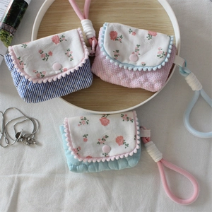 Detail of floral quilted mini camera pouches with colorful pom-pom trim and wrist straps
