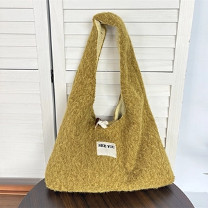 Detailed shot of yellow plush shoulder bag with wood button closure and plaid lining