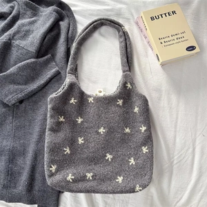 Close-up of the grey tote bag with white bow embroidery and black-and-white checked lining