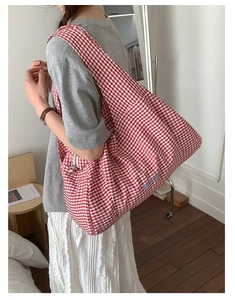 Detail of red gingham canvas tote bag with blue embroidery and wide shoulder strap
