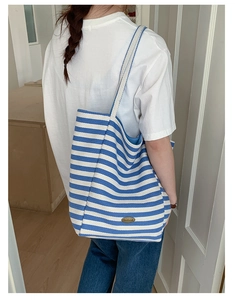 Détail du sac cabas en toile rayé bleu et blanc avec étiquette faite main porté à l'épaule