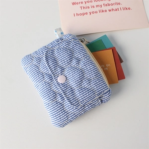 Detail of blue striped quilted coin purse with button accent and top zipper closure