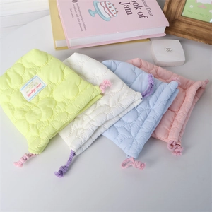 Close-up of heart-quilted drawstring pouches in lime, cream, blue and pink soft fabric