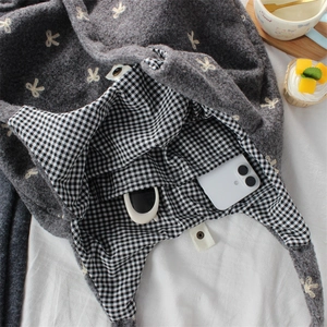 Detail view of bow embroidery tote with plaid lining, inner pocket, and magnetic closure